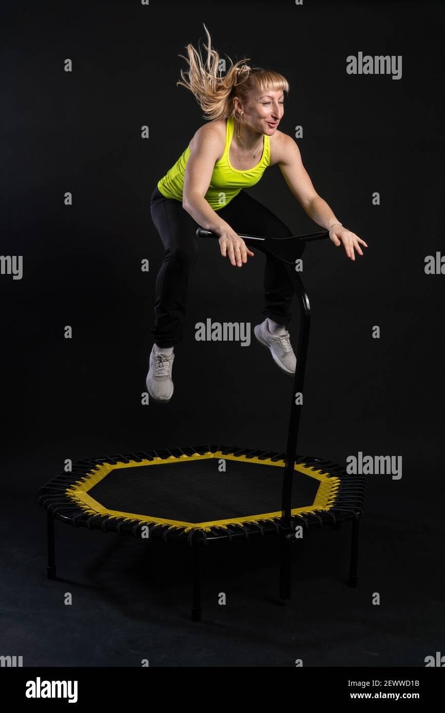 Girl on a fitness trampoline on a black background in a yellow t-shirt trampoline  sport, equipment activity female lifestyle vitality, cute rebounder Stock  Photo - Alamy