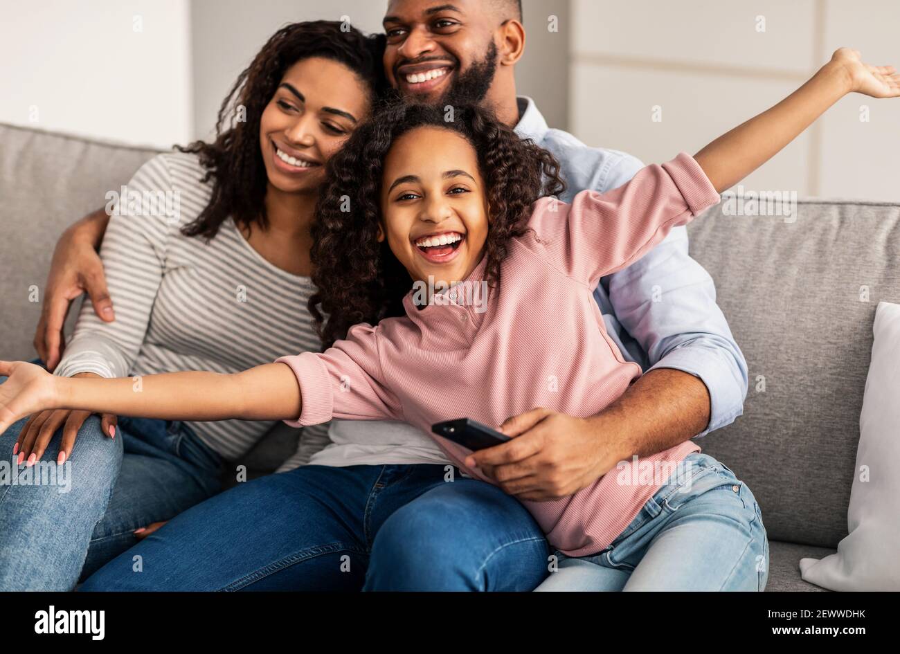 Happy young family watching television sitting on sofa Stock Photo