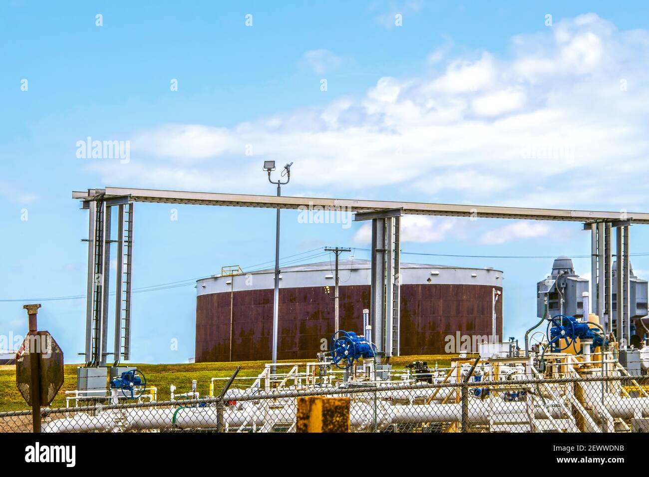 Rusty oil tank at tank farm in Cushing Oklahoma with valves and pipes and overhead rail at pipeline loading facility where most of USA WTI crude is st Stock Photo