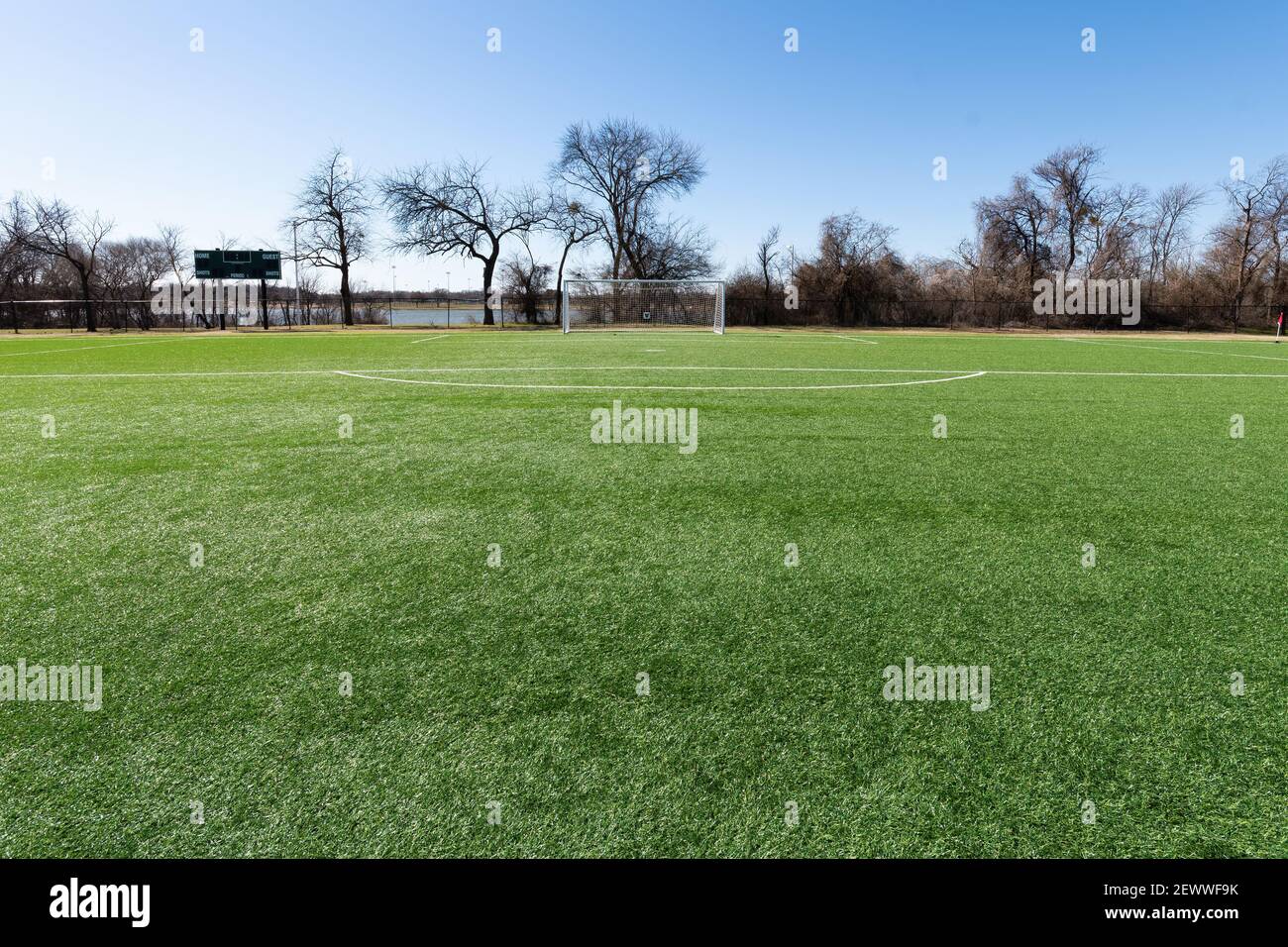 Soccer goal on a field with artificial grass in a city park with trees and a lake in the background. Stock Photo