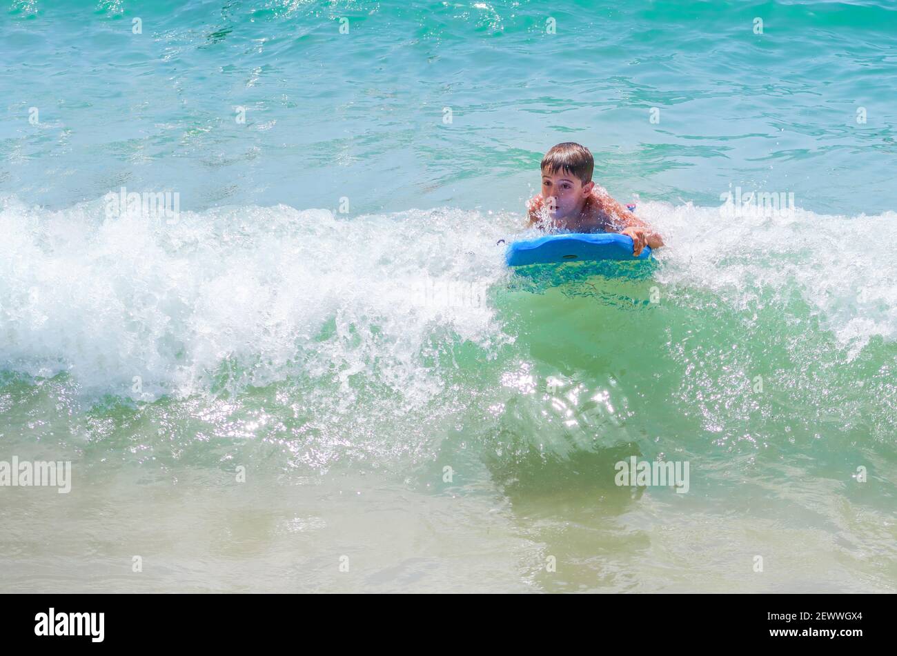 boy bodyboarding a wave on a turquoise water beach on a sunny summer day, bodysurfing, copy space horizontal Stock Photo
