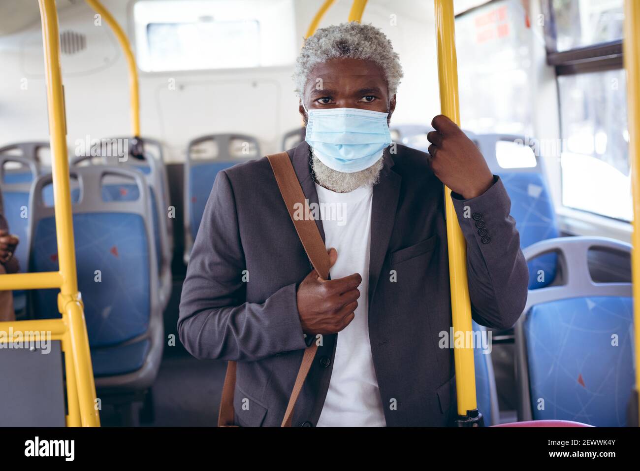 African american senior man wearing face mask standing on bus Stock