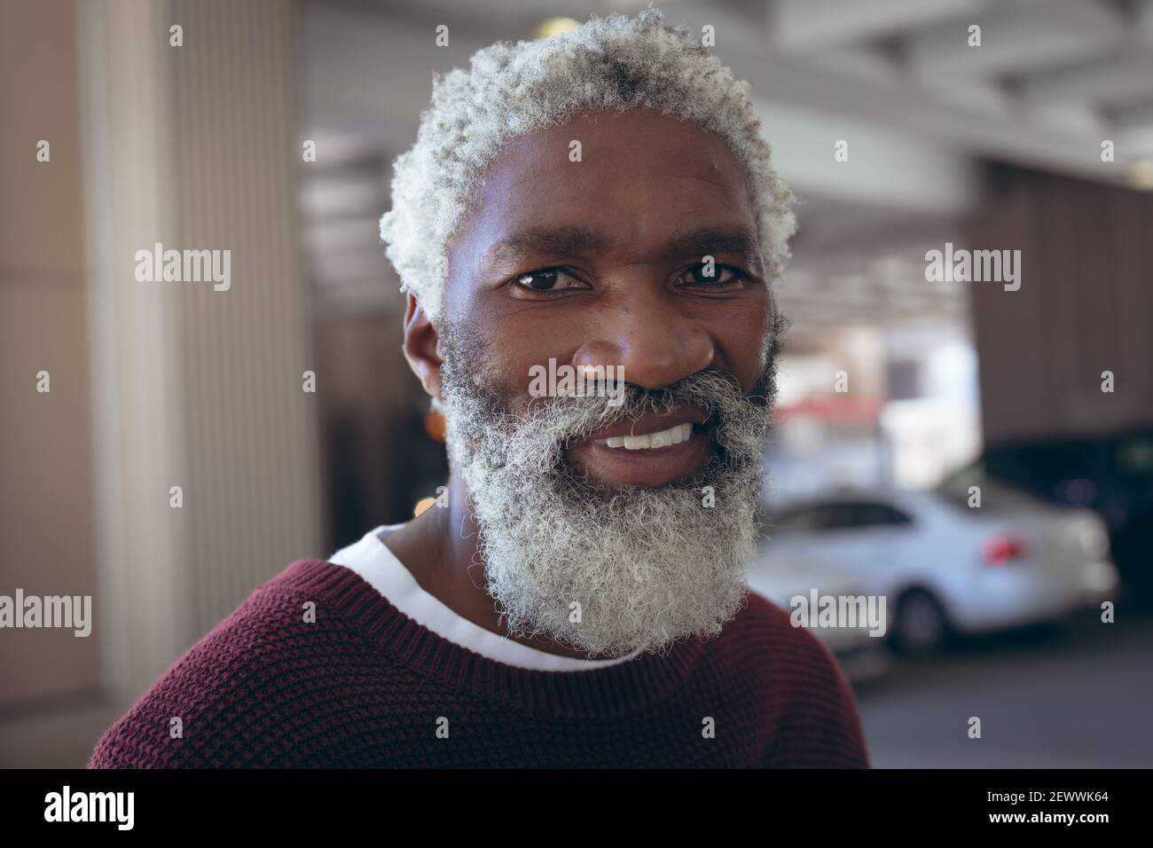 Portrait of casually dressed african american senior man with beard smiling in street Stock Photo