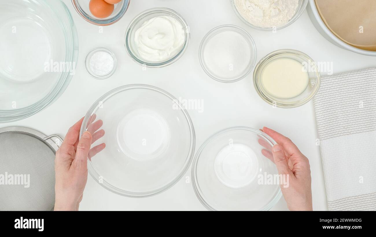 Ingredients and dishes for making  cake close up on kitchen table, view from above. Step by step chocolate cake recipe, woman hands Stock Photo