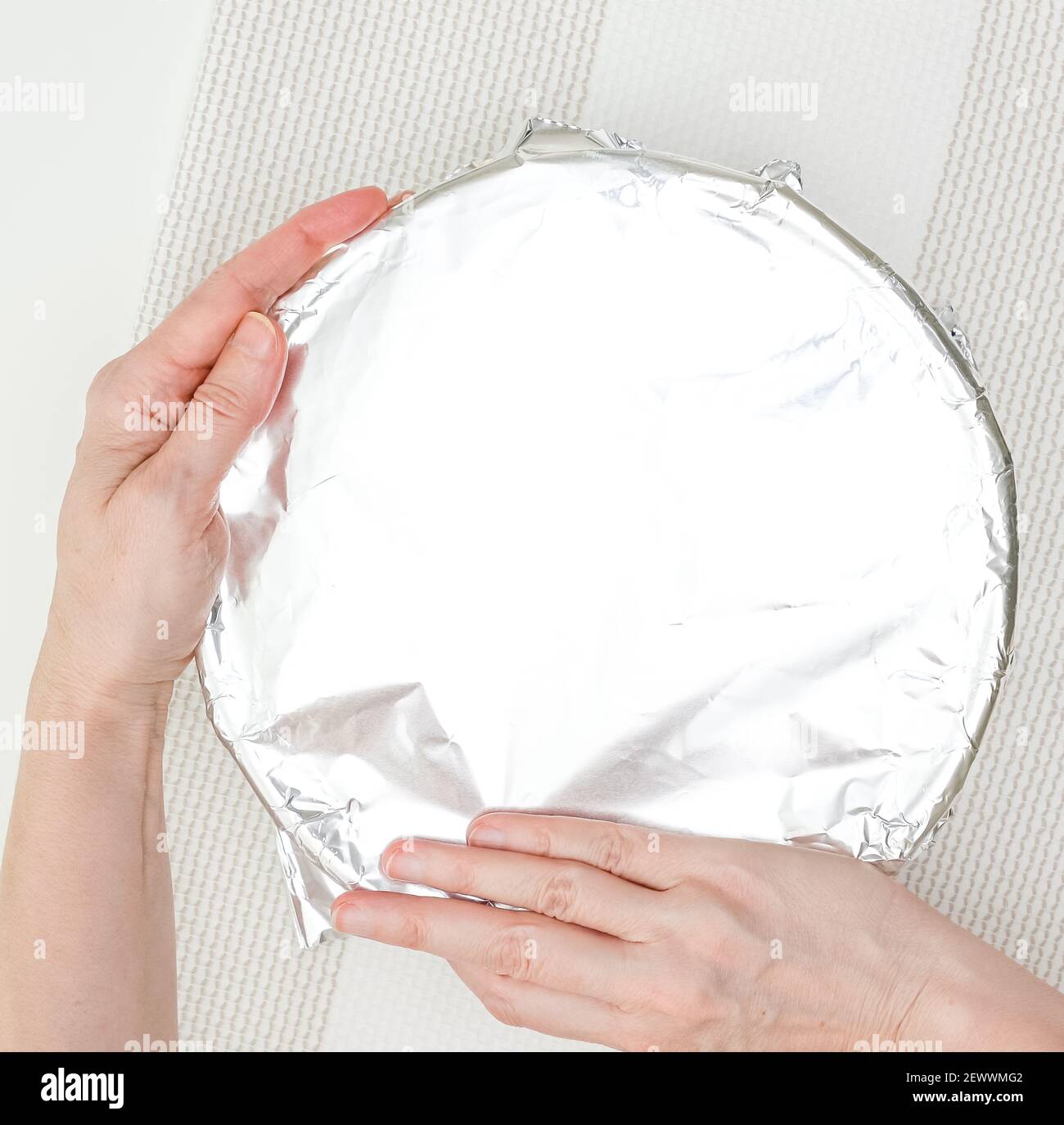 Aluminum foil wrapped over baking pan. Close up baking process, woman