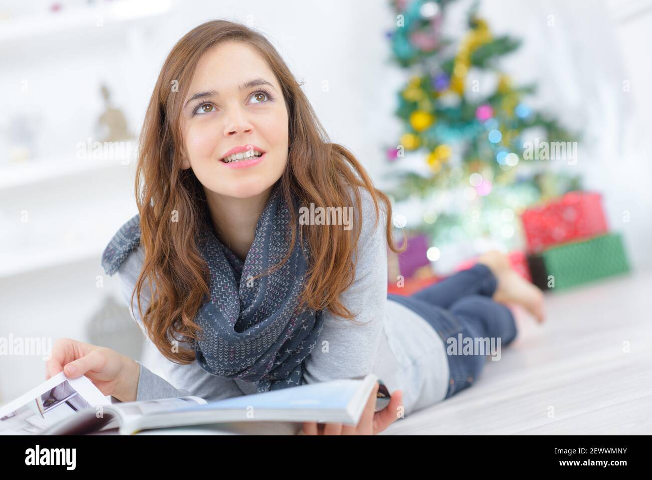 woman layed on floor flicking through magazine at christmas Stock Photo