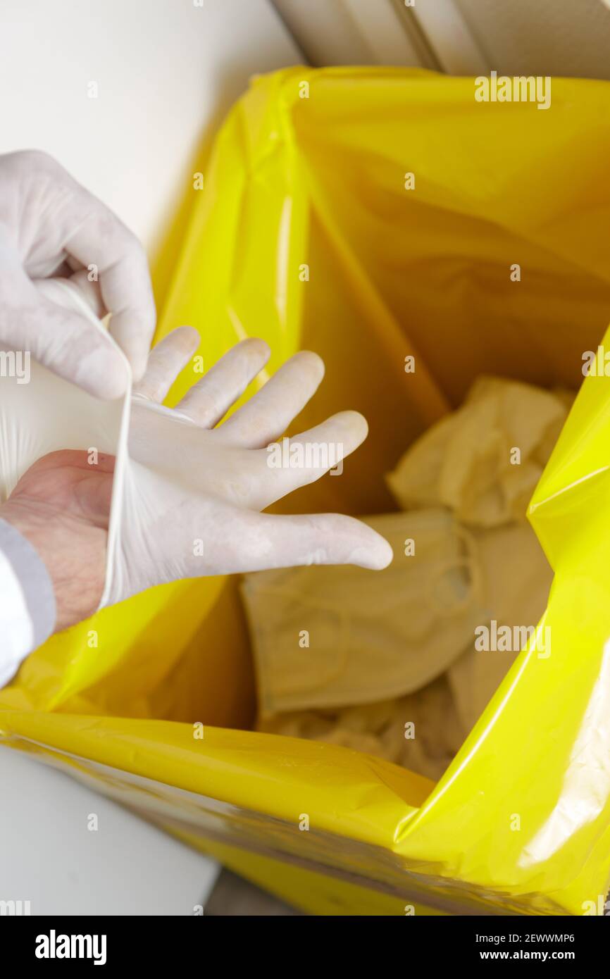 medic removing glove into bin with yellow liner Stock Photo