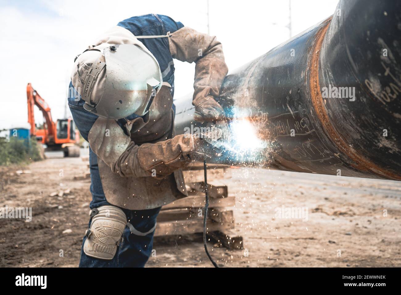 Men welding a water pipe outdoors with protective clothes Stock Photo