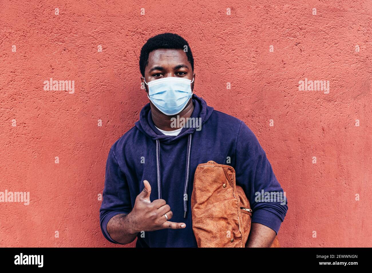 Portrait of an African American boy with face mask on red wall background. Stock Photo