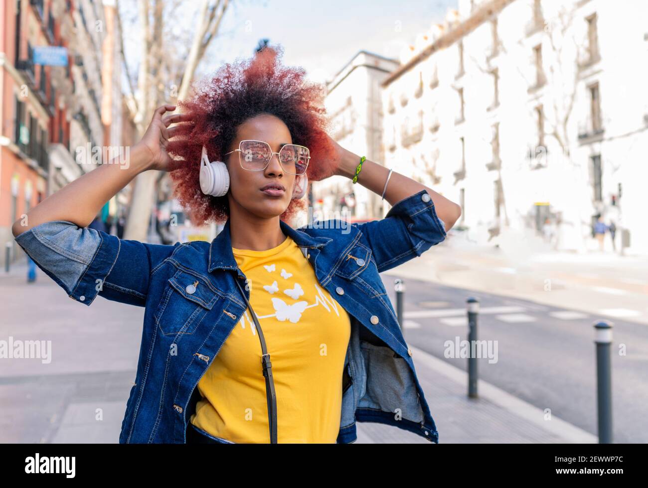 woman with afro hair listening to music with her headphones in the city Stock Photo