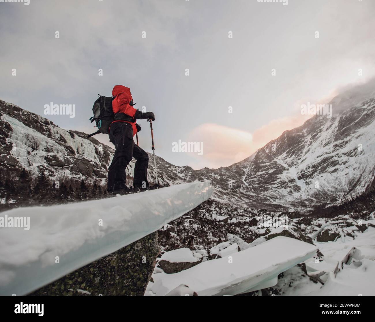 Man on snowshoes stands on frozen ice block in winter, Katahdin Maine
