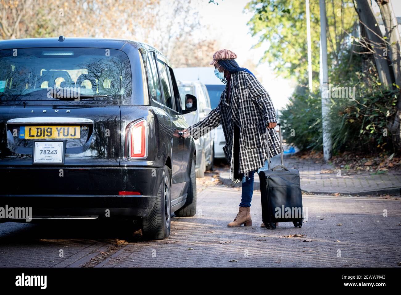 A woman uses a black cab in Canning Town, London. Stock Photo