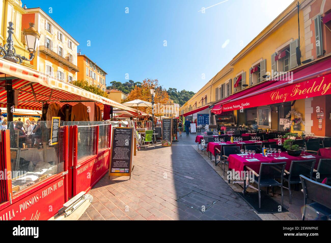 A sidewalk cafe in the Cours Saleya old town Vieux Nice, France, area on a summer morning next to the weekly outdoor market. Stock Photo