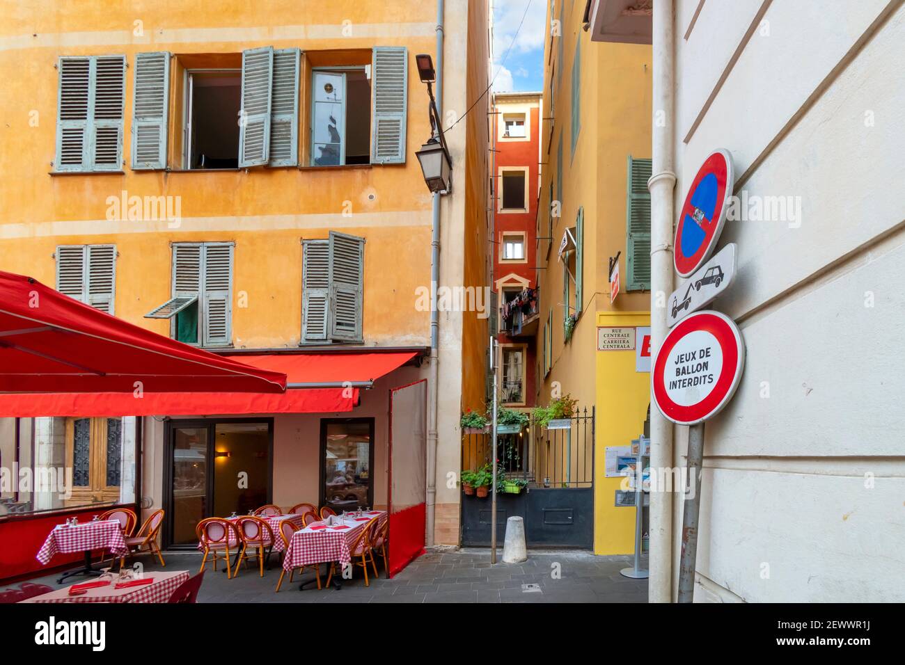 A very narrow gated courtyard at an apartment alongside a sidewalk cafe in the Old Town Vieux Nice section of France, on the French Riviera. Stock Photo