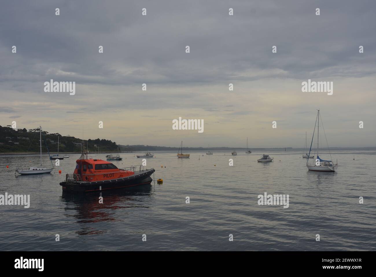 Recreational and commercial boats moored in calm bay in late evening when holidaymakers are gone. Stock Photo