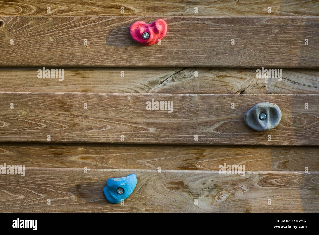 A closeup shot of a climbing wall with colorful hanging rocks isolated on the wooden material Stock Photo
