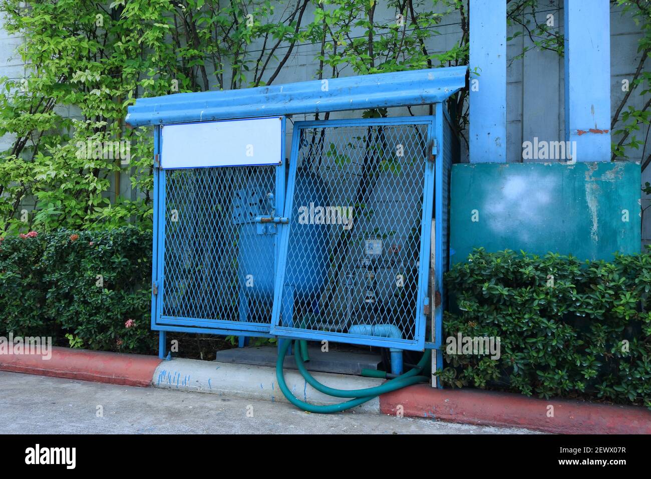 Damaged chain-link fence door with broken hinge used for protecting water pump in the garden Stock Photo