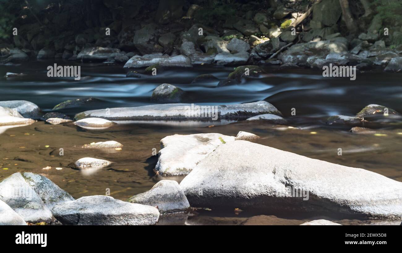 Smooth Stream Rocks A selective focus shot of rocks in a stream with smooth flowing water ...