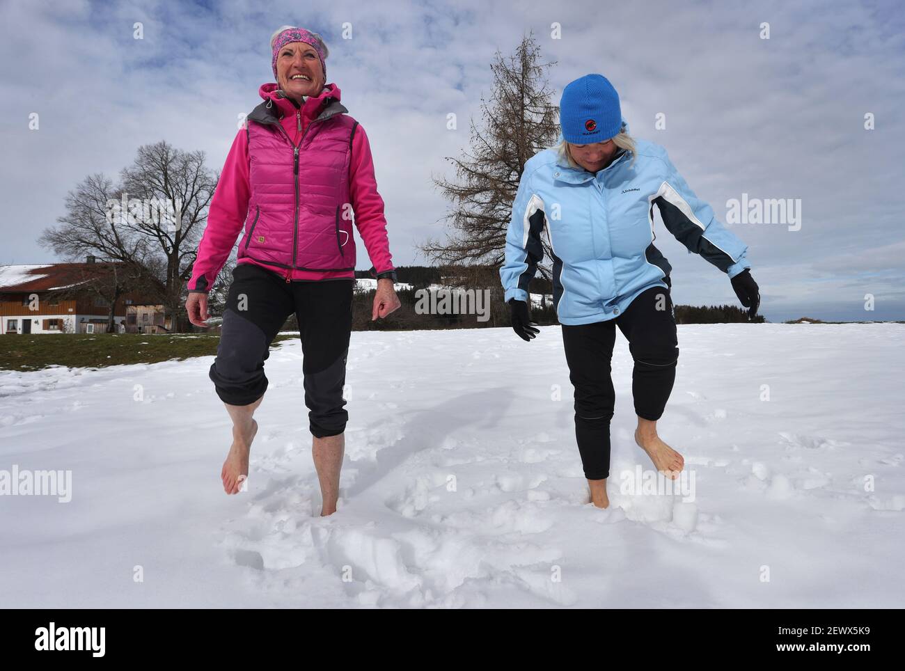 Wiggensbach, Germany. 16th Feb, 2021. Ida-Anna Braun (r), chairwoman of the Kempten Kneipp Association, and Monika Weitnauer, secretary and Nordic walking leader of the association, walk barefoot through the snow in front of the panorama of the Alps. (to dpa 'Kneipp associations struggle for image and members in anniversary year') Credit: Karl-Josef Hildenbrand/dpa/Alamy Live News Stock Photo