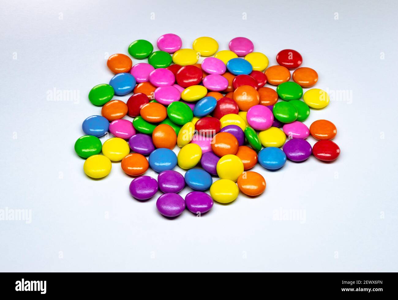 Selective focus of colorful chocolate buttons on a white paper background. Stock Photo