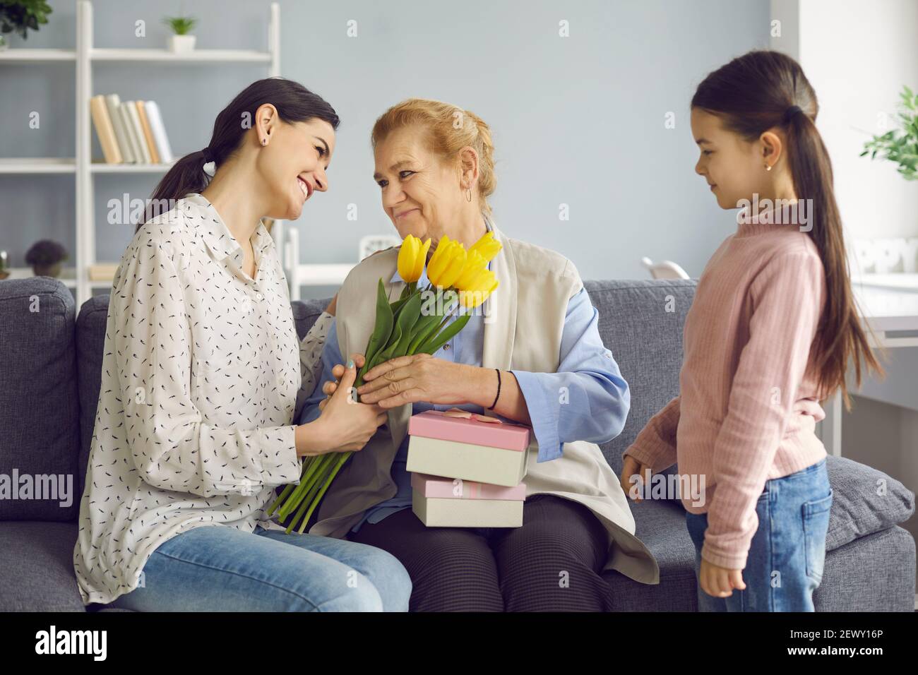 Happy older woman receives gifts in honor of Mother's Day or International Women's Day. Stock Photo
