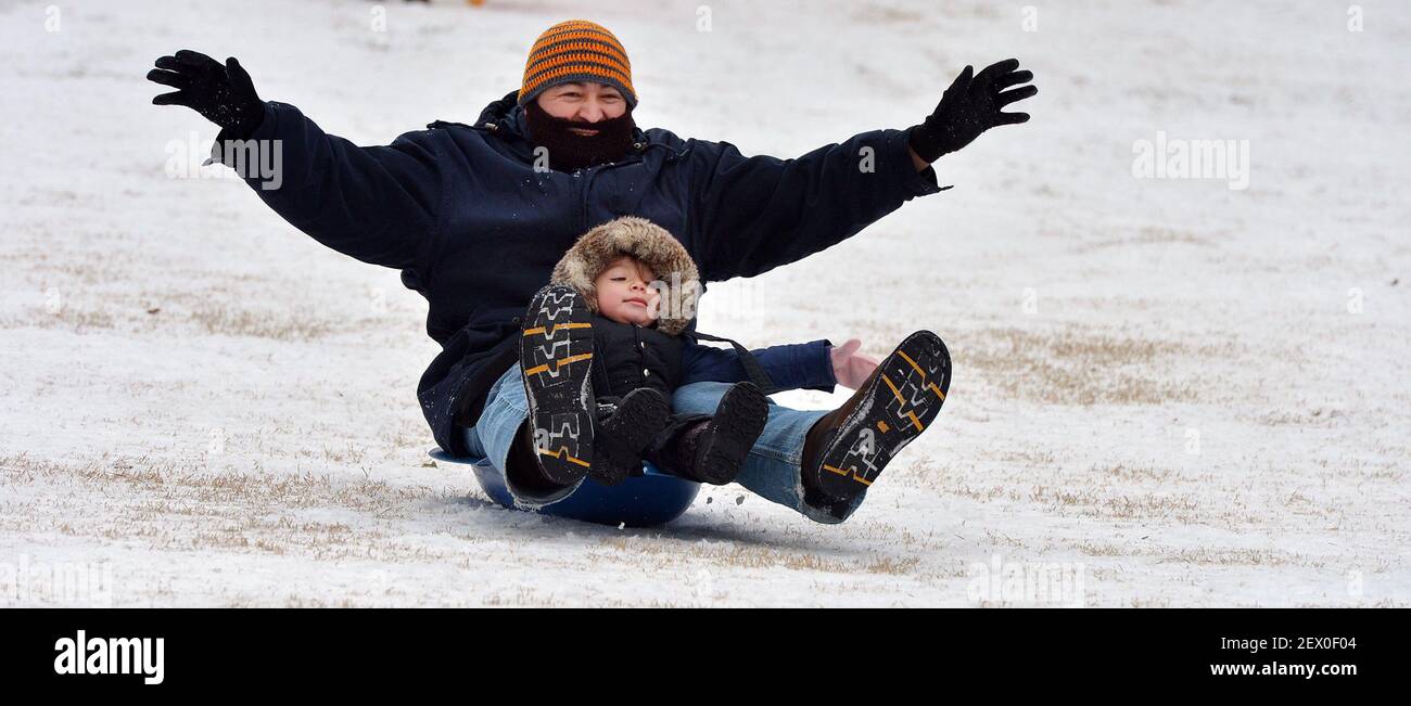 Edgar Hernandez and daughter Emily, 2, enjoy riding a sled on Tuesday, Feb. 17, 2015 in Durham, N.C. A winter storm that made it's way across the region Monday night made roads and sidewalks hazardous. (Photo by Chuck Liddy/News & Observer/TNS) *** Please Use Credit from Credit Field *** Stock Photo