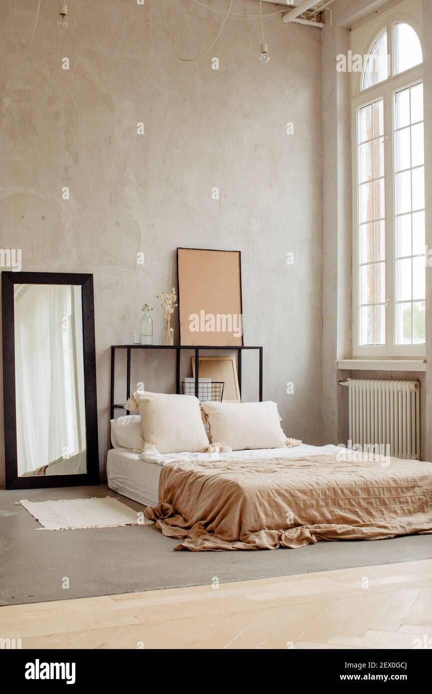 Empty wide bed with soft pillows and cute linens in big room with light