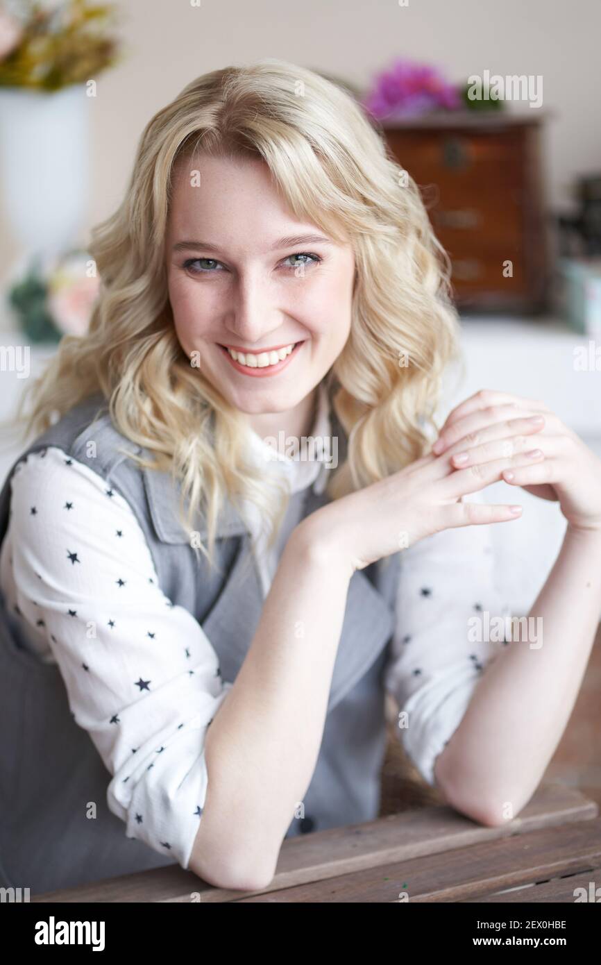 Beautiful blonde specialist sits at a table and smiles, a woman looks into the frame Stock Photo