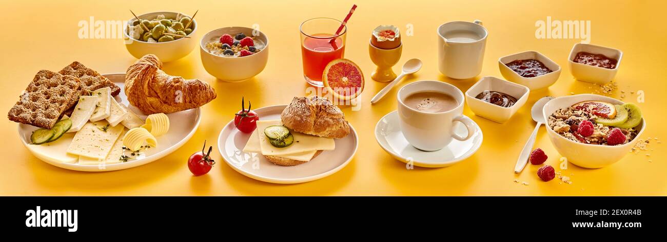High angle of assorted food and drinks for breakfast arranged on bright yellow background Stock Photo