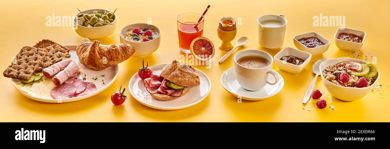 From above composition of various breakfast food and drinks placed on yellow background in morning Stock Photo