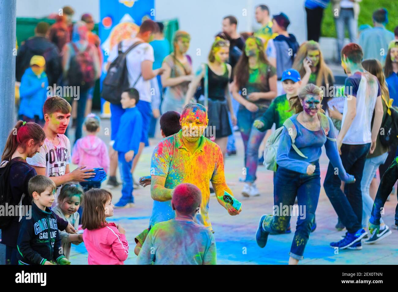 Russia, Moscow - June 25, 2017. Cheerful, young people throw themselves bright colors. Happy faces of adults and children are stained with paint. Holi Stock Photo