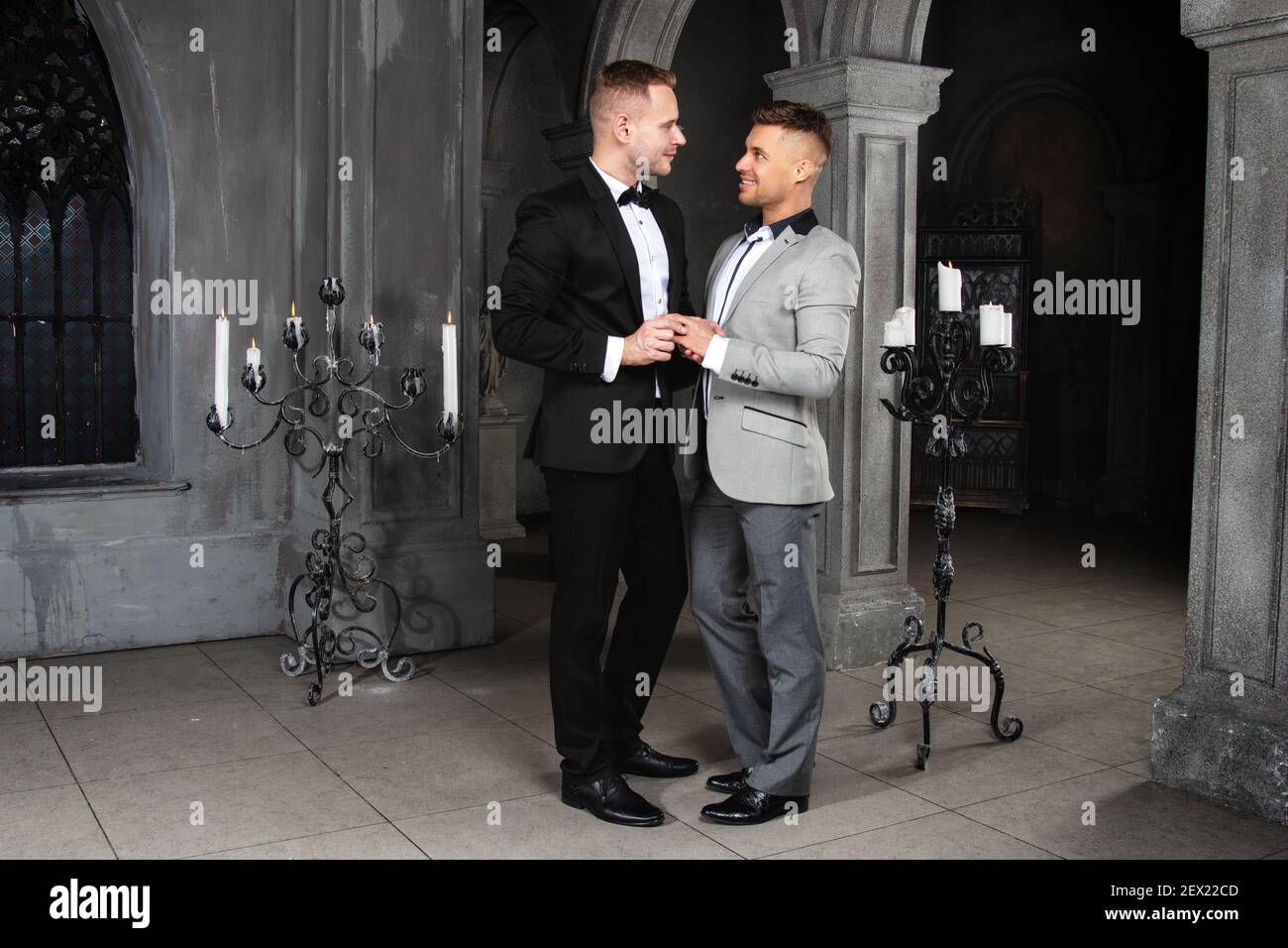Young happy gay couple getting married in church. Love and romance. Handsome men in suits. Stock Photo