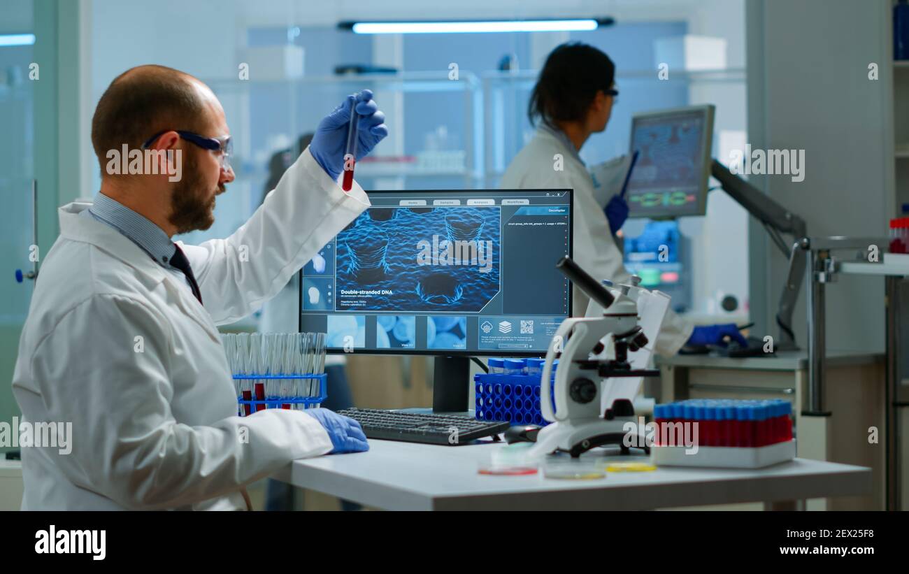 Scientist man examining blood samples and liquid working in modern ...