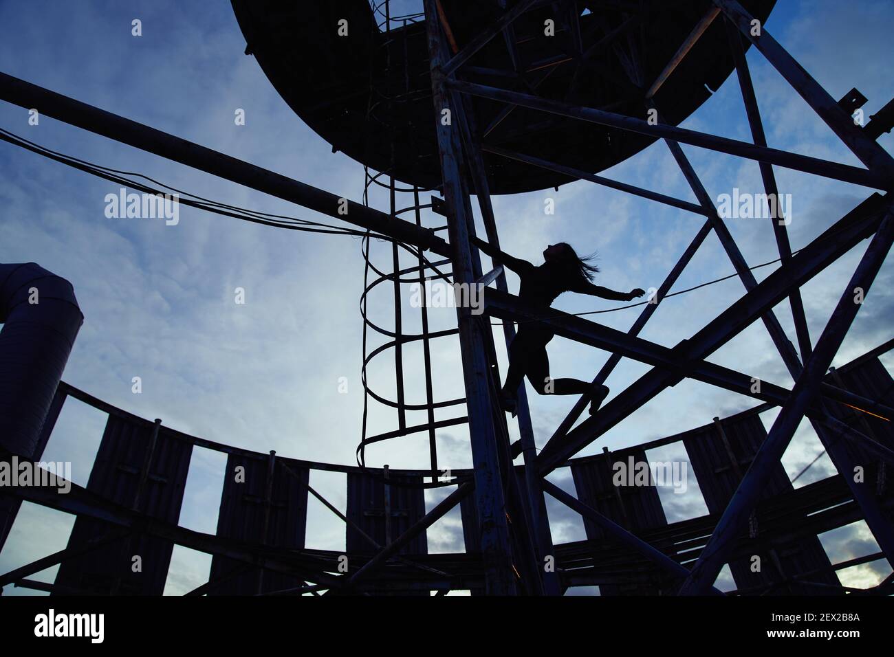 Silhouette of alpinist female climbing high risk building against a ...