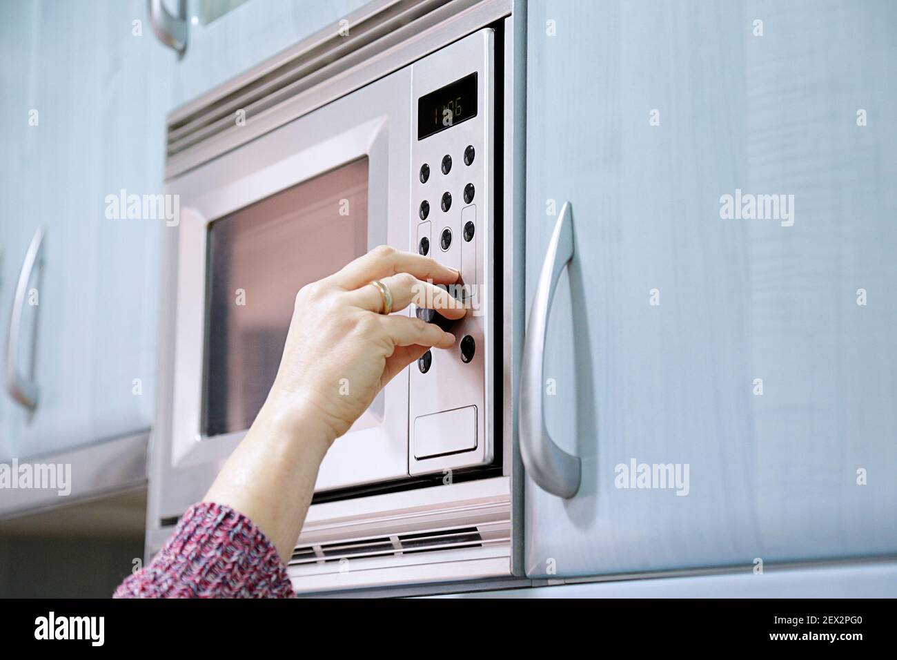 Woman using microwave oven at home. Stock Photo