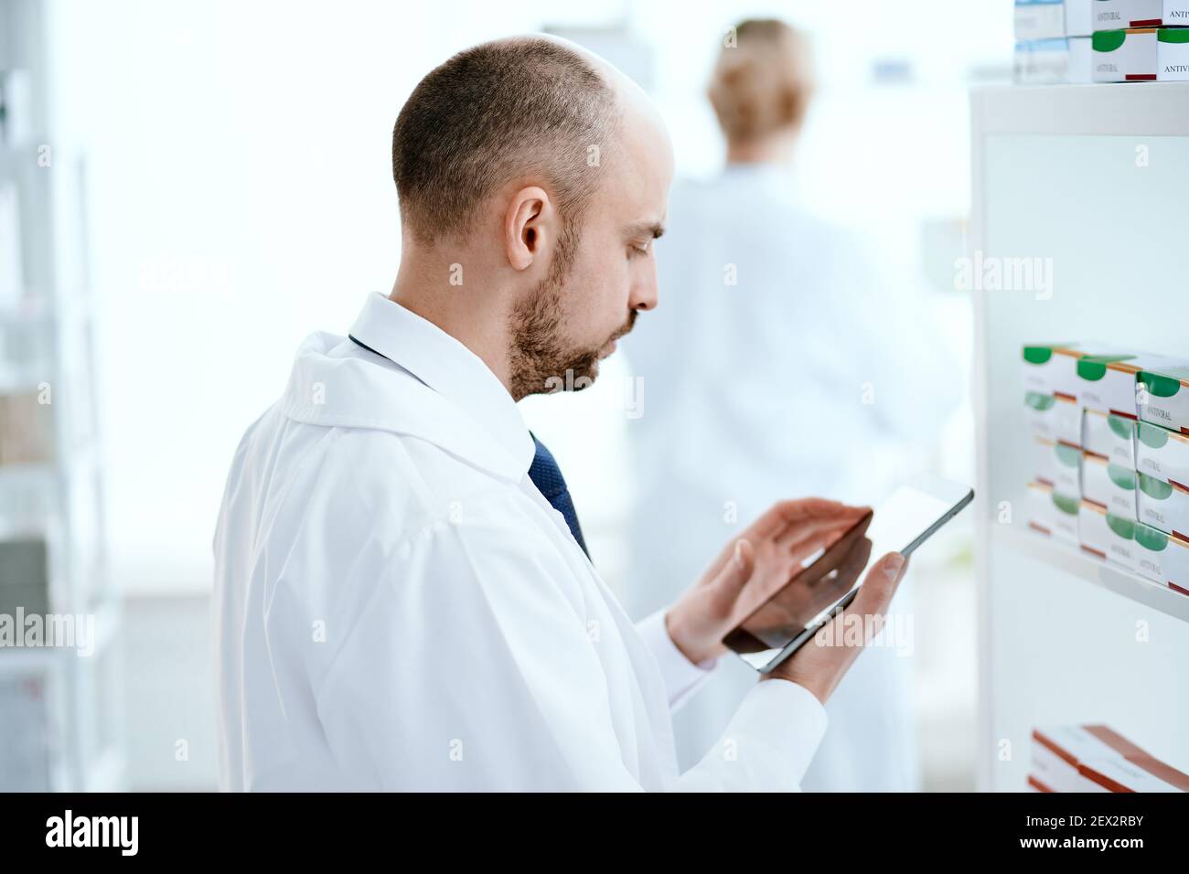pharmacist scrolling on digital tablet checking medication . Stock Photo