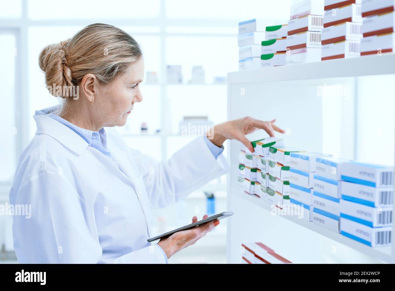 serious female pharmacist using a digital tablet in the workplace. Stock Photo