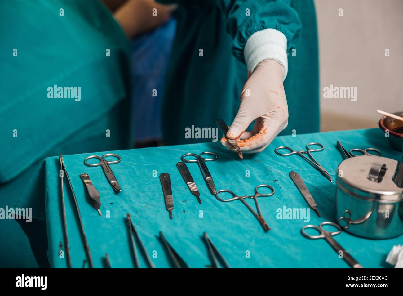 Surgeon hand wearing medical glove choosing surgical instrument on table in the operating room Stock Photo