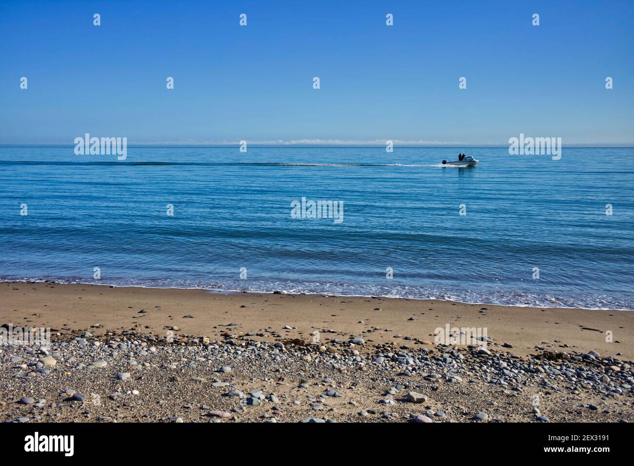 A small fishing boat on a clear February day speeds along heading back to Ramsey harbour, Isle of Man Stock Photo