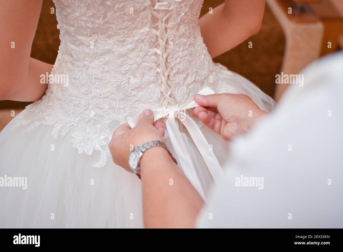 Wedding dress, corset. Mom ties a bow on the bride's dress.  Stock Photo