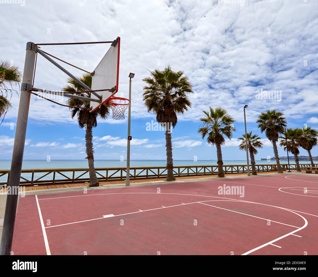 Outdoor street basketball court on beach in San Clemente California with orange surface and palm trees in the background showing hoop and backboard Stock Photo