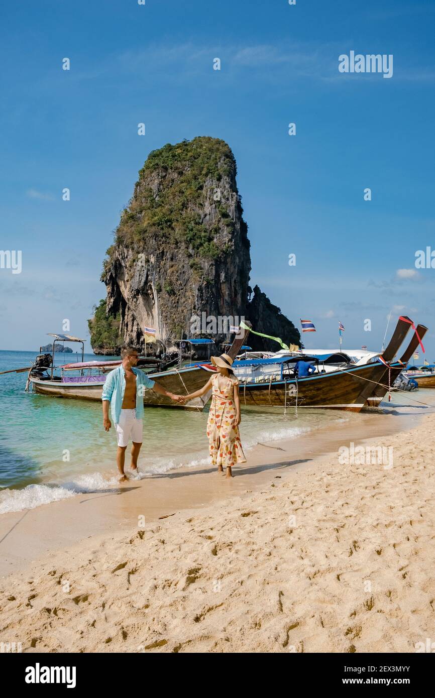 couple mid age on a tropical beach in Thailand, tourist on a white tropical beach, Railay beach with on the background longtail boat. Railay Beach in Krabi province. Ao Nang, Thailand. Stock Photo