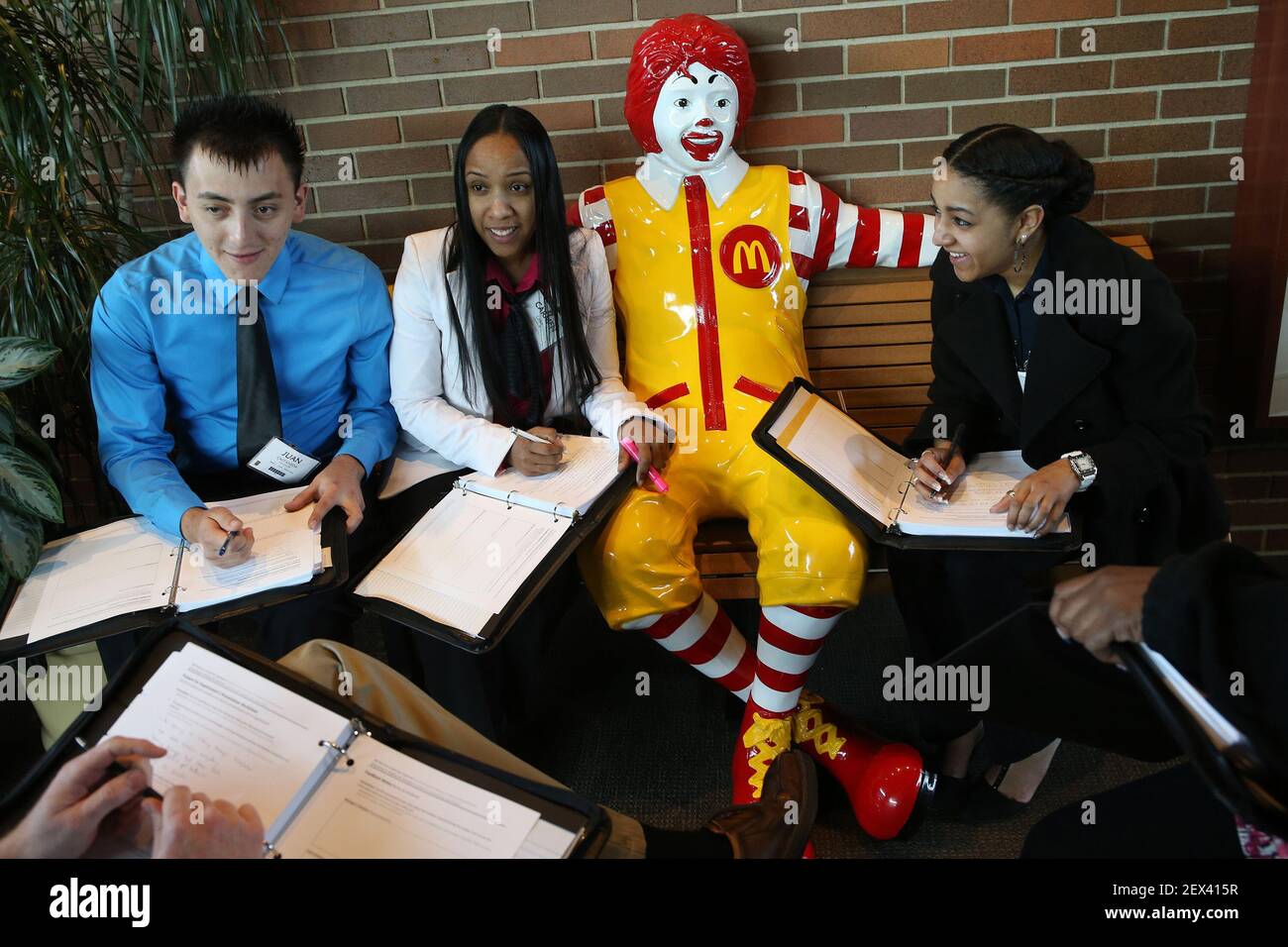 McDonalds restaurant general managers, from left, Juan Castaneda, Carmen  Caba and Joanna Molina meet as a team to consolidate their notes and  discuss as they gather around a Ronald McDonald statue at