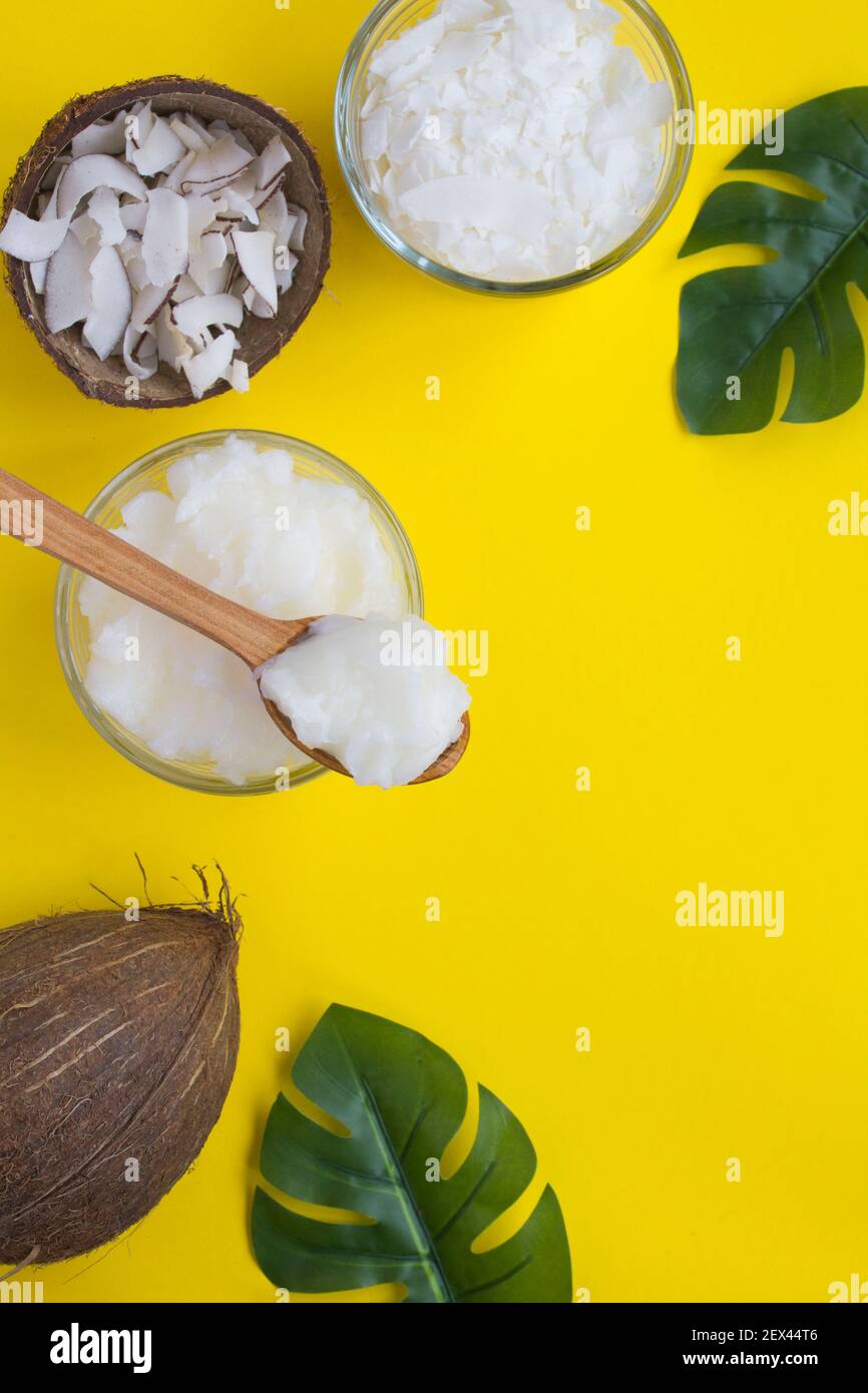 Coconut oil, coconut crisps and coconut flakes on the yellow background