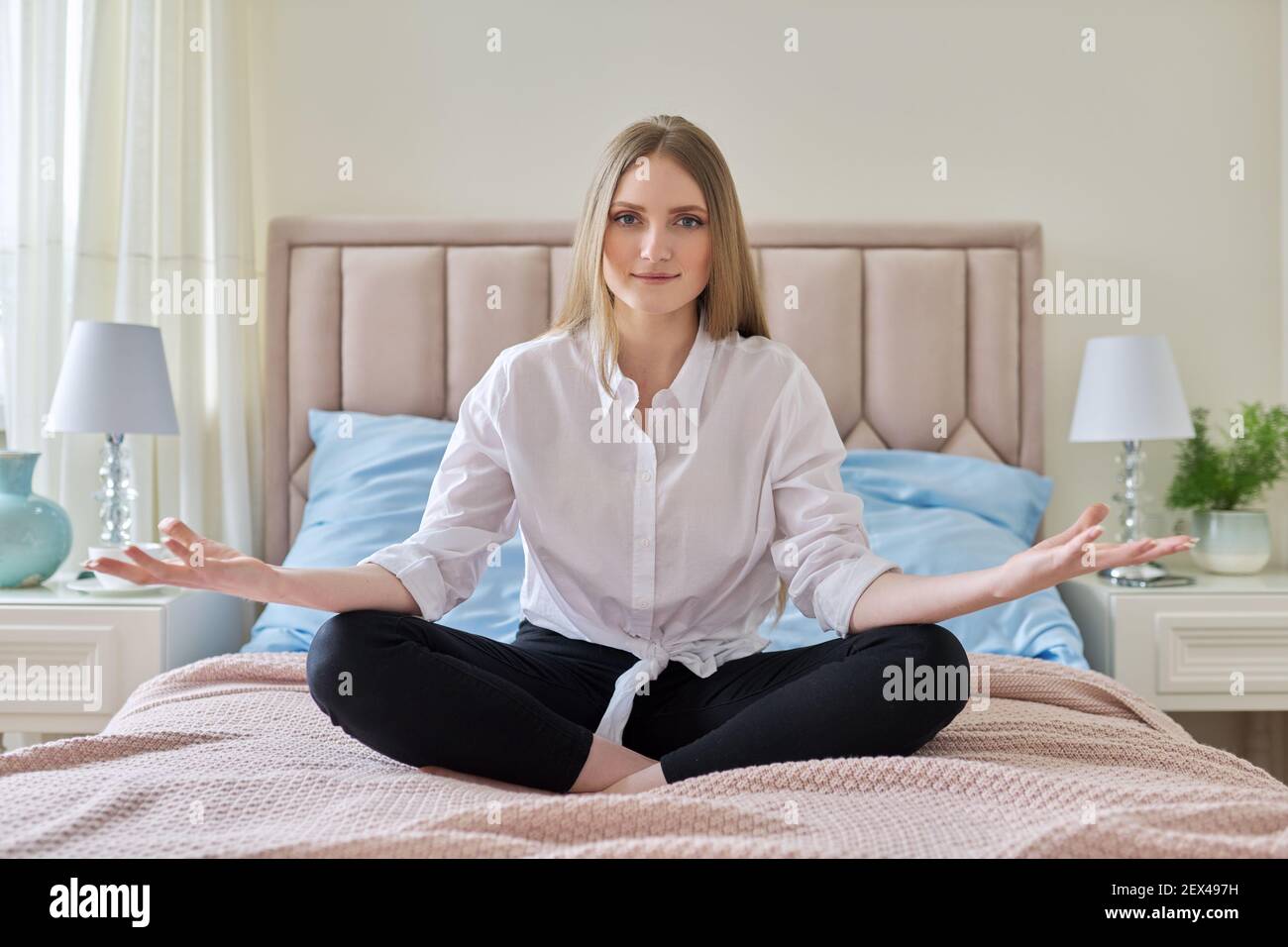Yoga meditation, young beautiful blonde woman sitting in lotus position ...