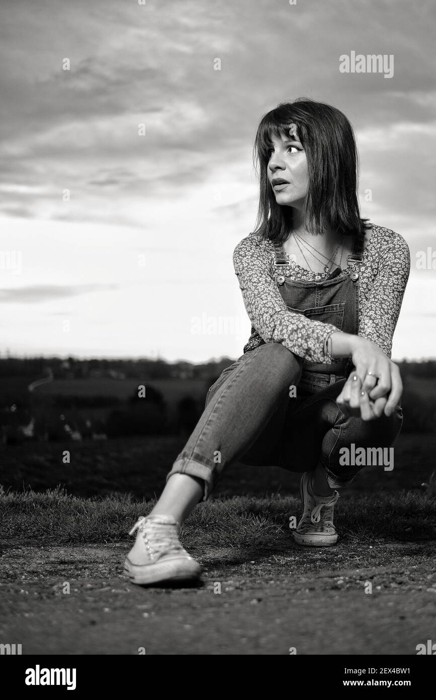 A surprised beautiful young woman crouched, in black and white Stock Photo