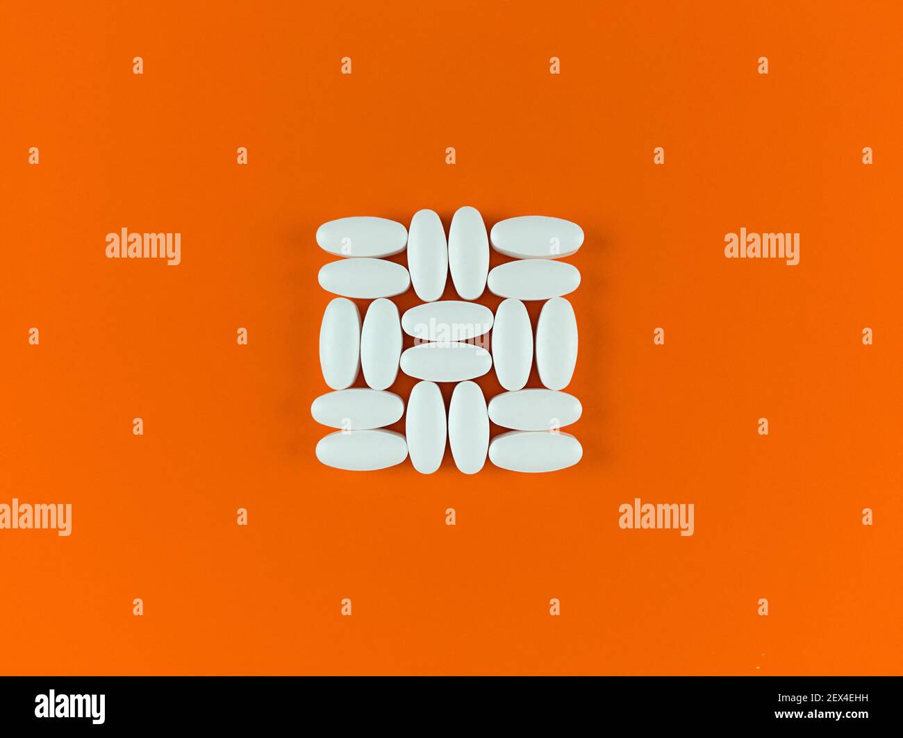 Square shape made from white tablets on orange backdrop. Stock Photo