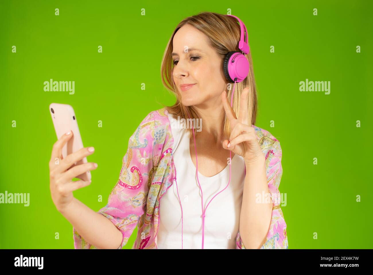 Happy young woman listening to the music isolated over green background ...