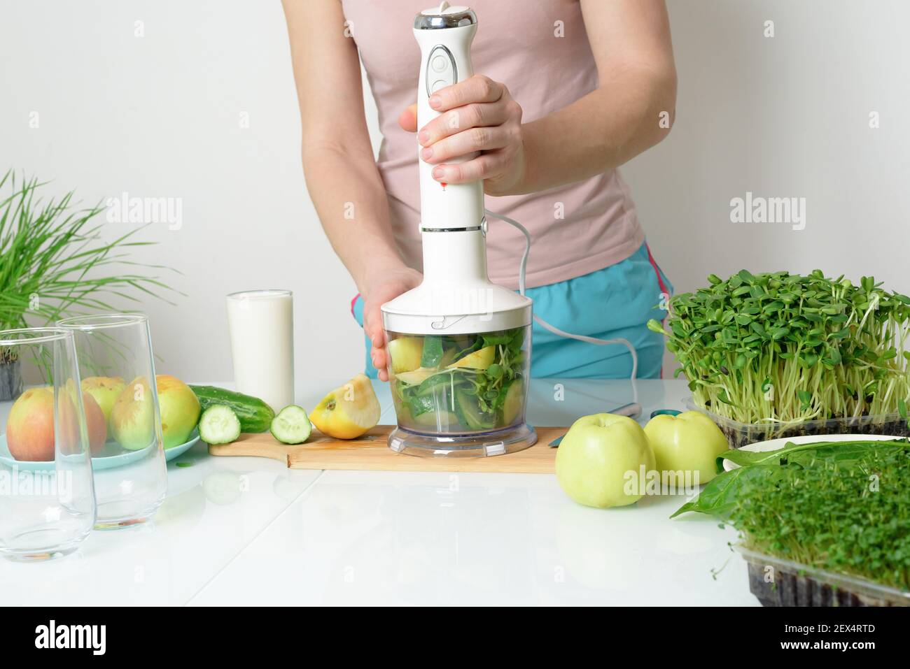 step-by-step recipe for making smoothies from micro-green apples cucumber and spinach. woman hands cut vegetables and put them in blender for whipping Stock Photo