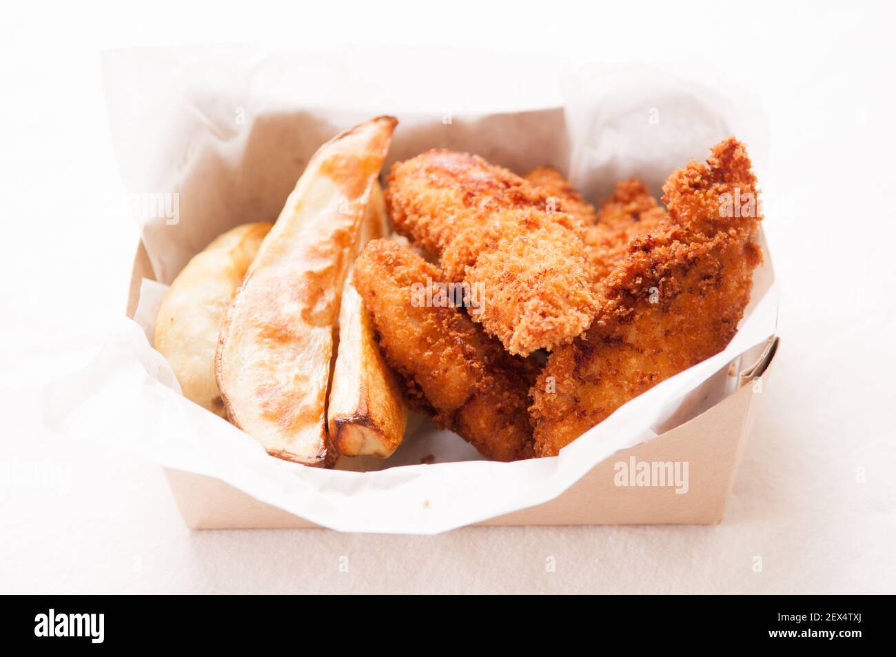 breaded chicken fingers and fries in a take out container Stock Photo